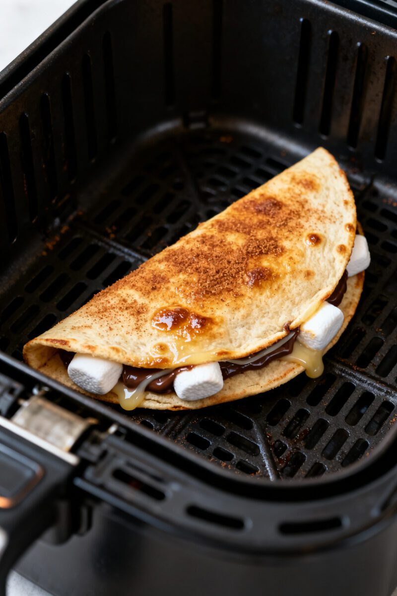 Close-up detail shot: A just-air-fried s’mores quesadilla resting in the open air fryer basket at
