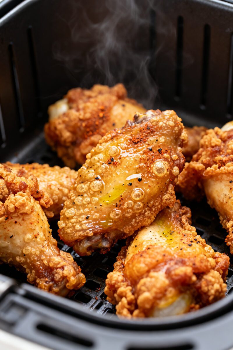 Close-up detail: Ultra-crispy air-fried chicken wings just out of the basket, skin deeply golden wit