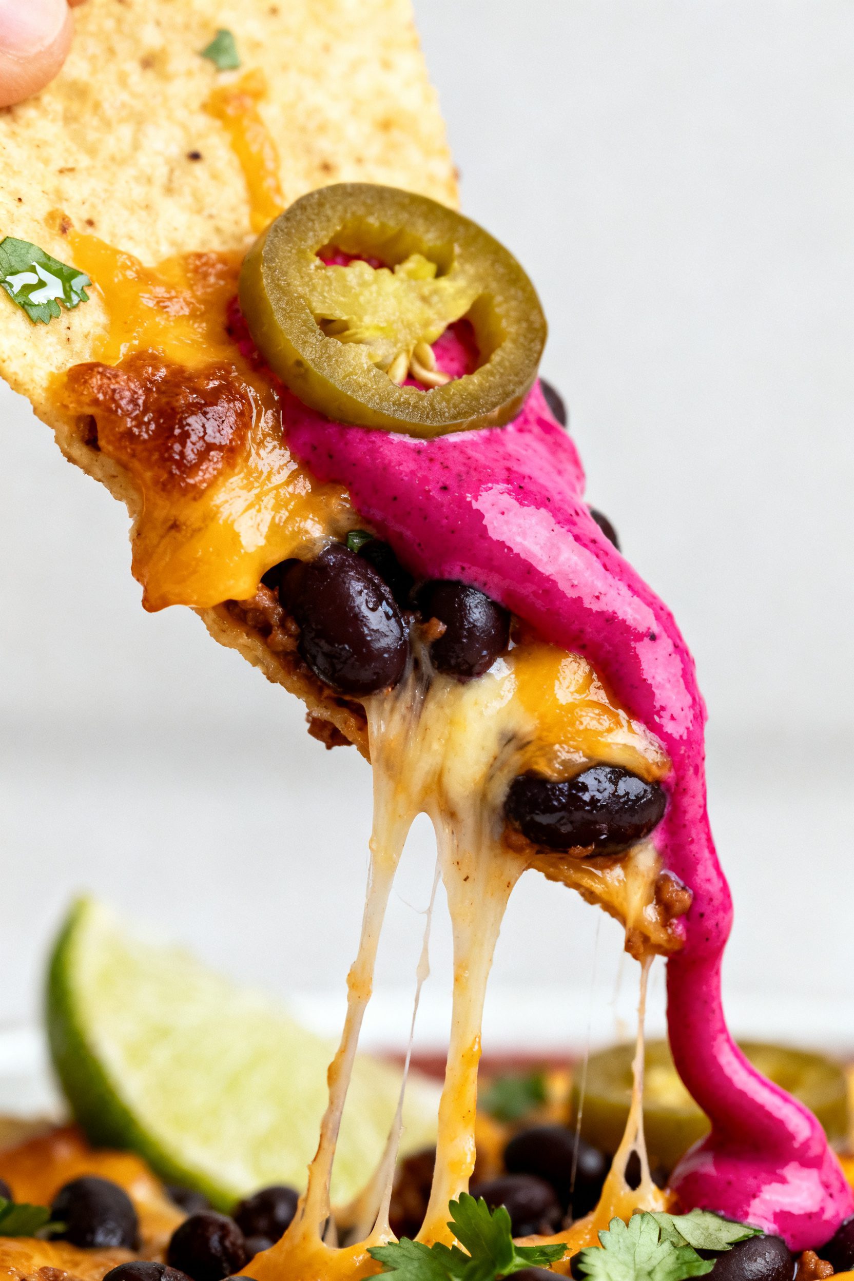 Close-up detail — Ultra-tight macro of a nacho chip pulled from the platter, showcasing layers: bu
