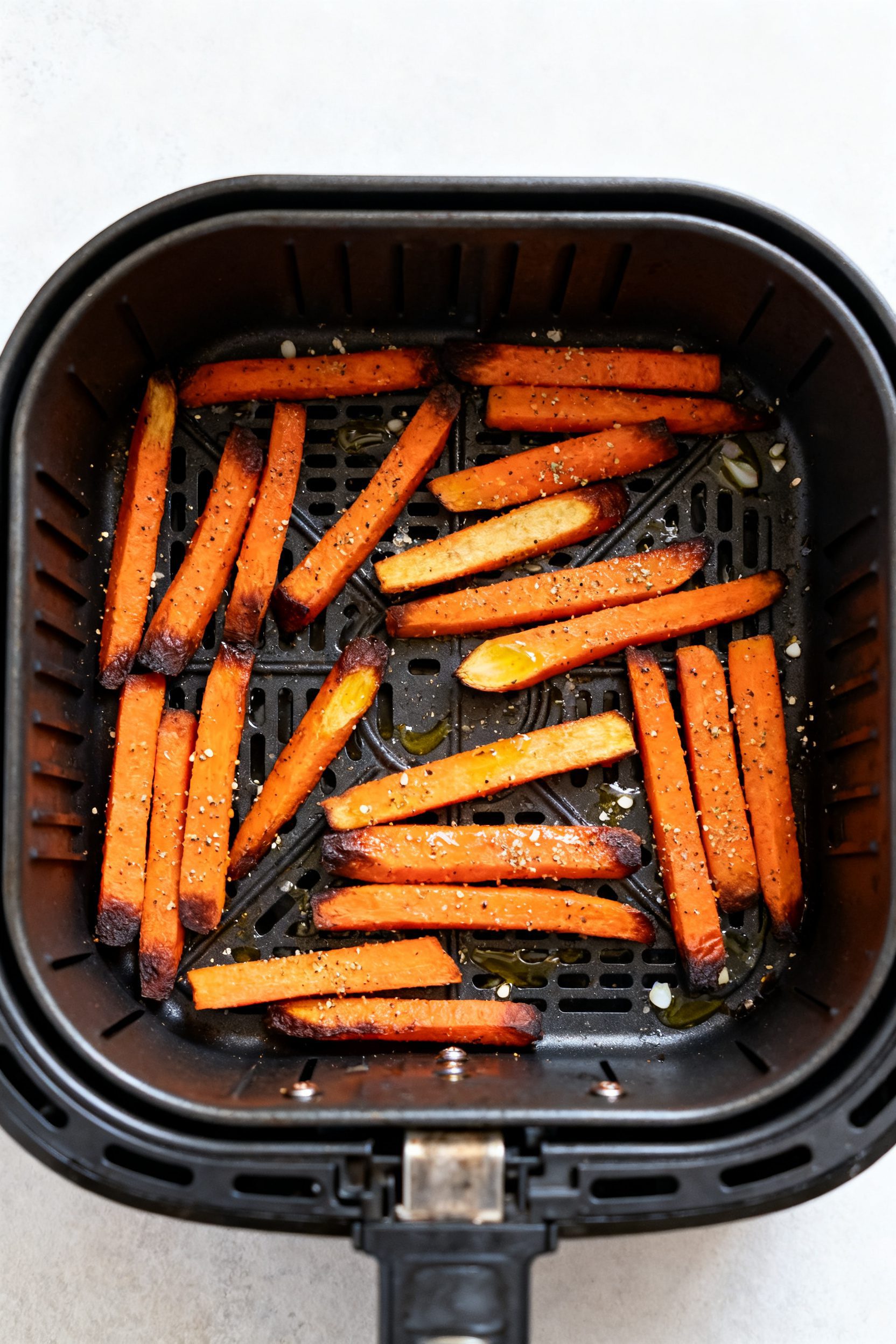 Cooking process: Air fryer basket in a single layer load, seasoned carrot sticks mid-cook at 400°F 