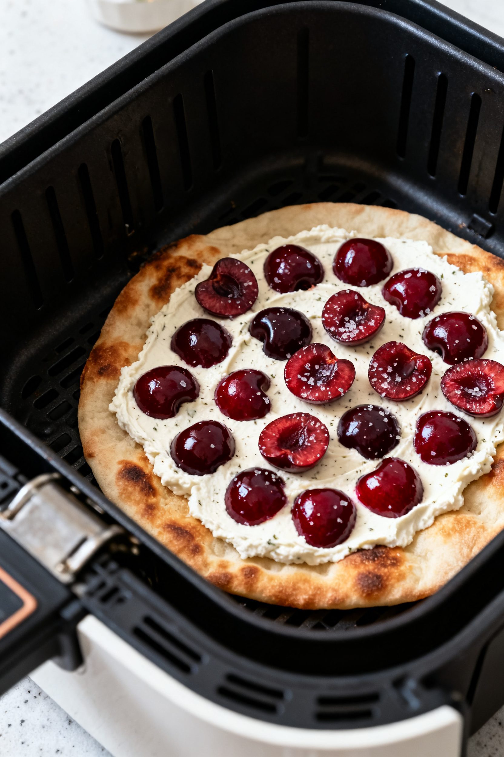 Cooking process: Air fryer basket with a par-cooked flatbread base just turning golden at the edges,