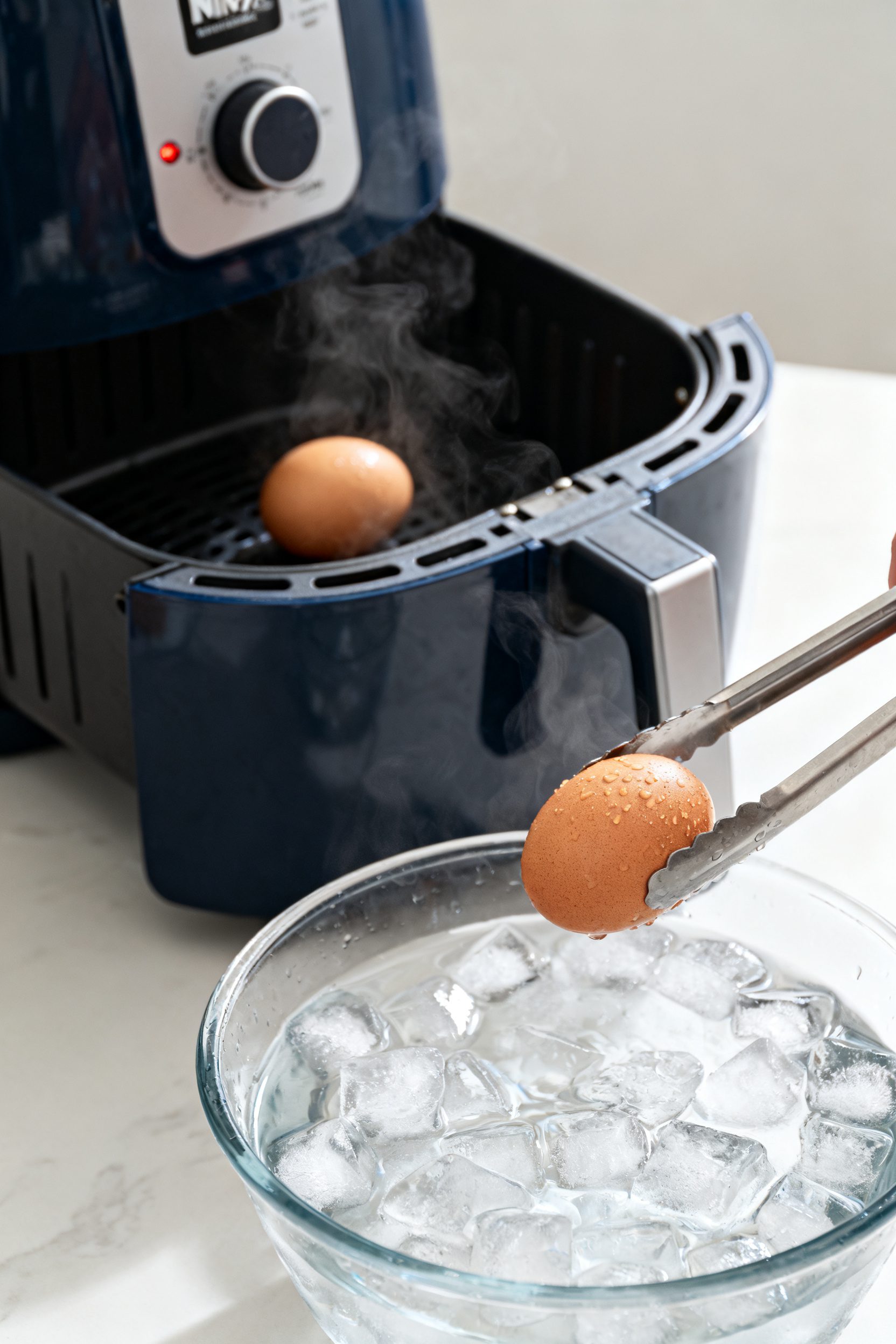 Cooking process close-up: Ninja air fryer basket with a single layer of cooked hard boiled eggs just