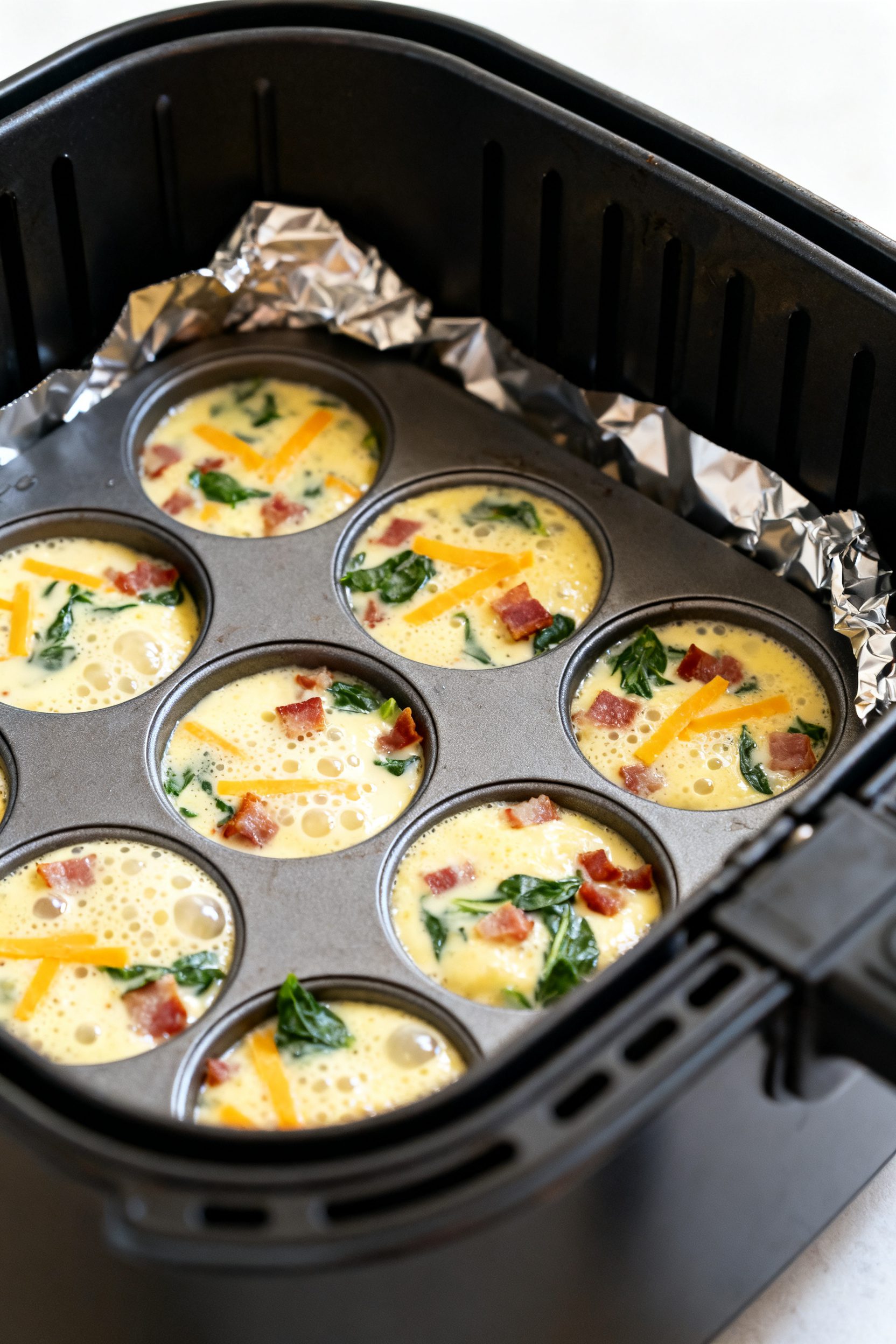 Cooking process close-up: Silicone egg bite mold inside an air fryer basket at 310°F, cups filled 8