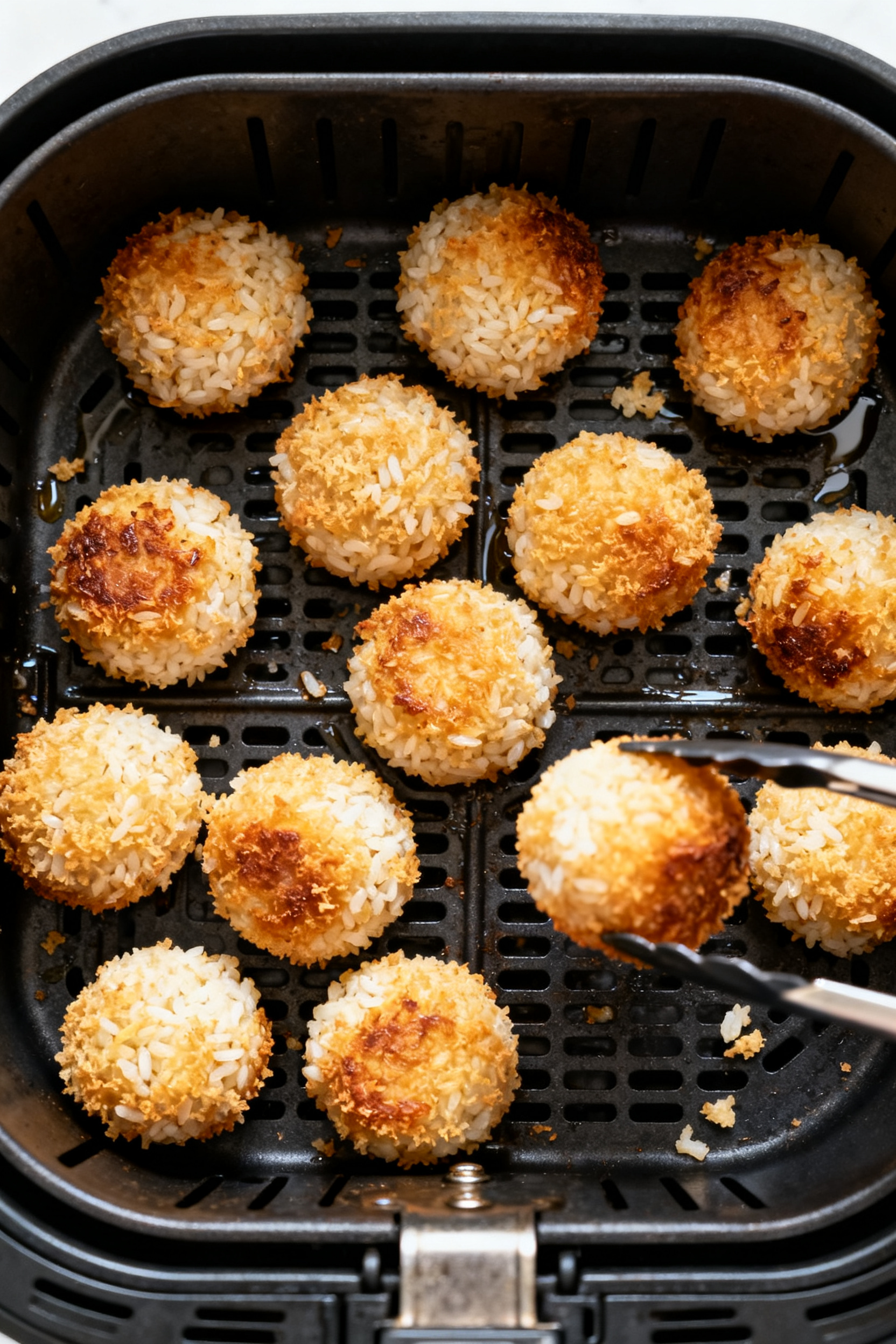 Cooking process: Overhead shot of a preheated air fryer basket with evenly spaced, fully coated rice