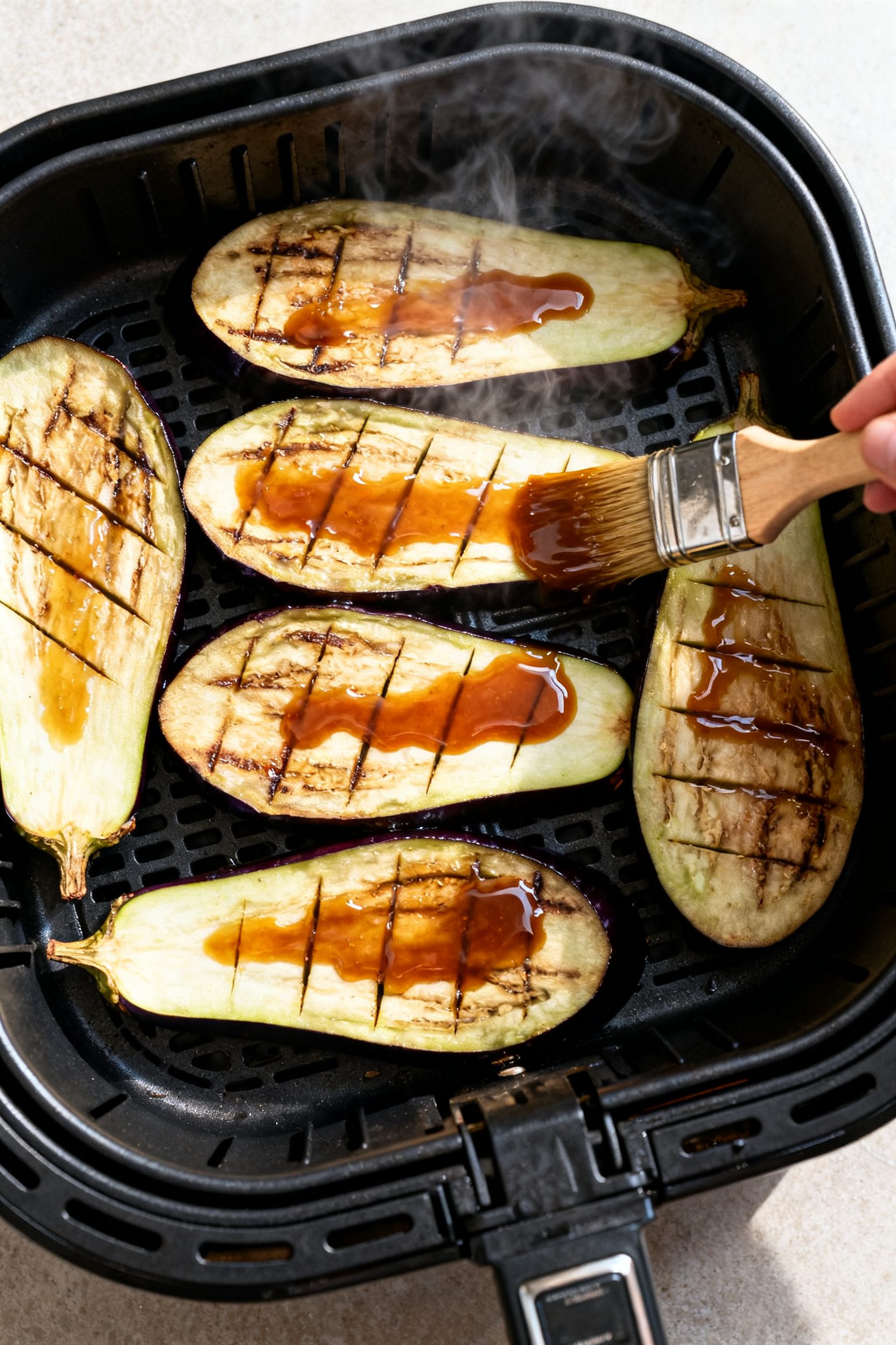 Cooking process: Overhead shot of an air fryer basket at 400°F holding neatly arranged eggplant hal