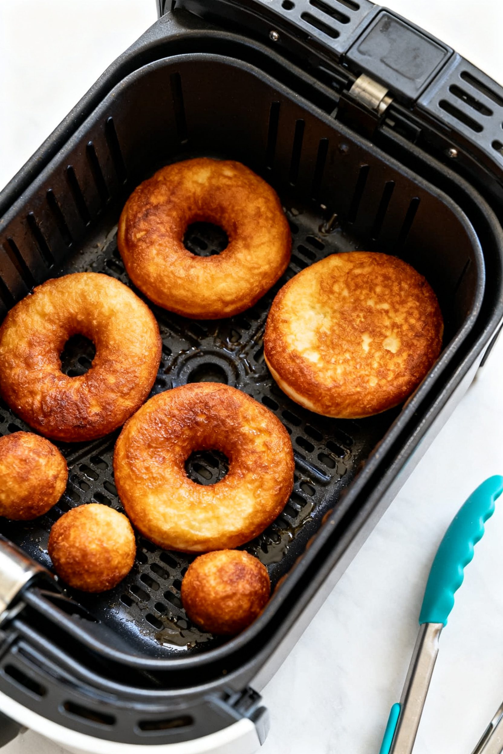 Cooking process: Overhead shot of an open air fryer basket at 350°F with 3–4 evenly spaced donut 