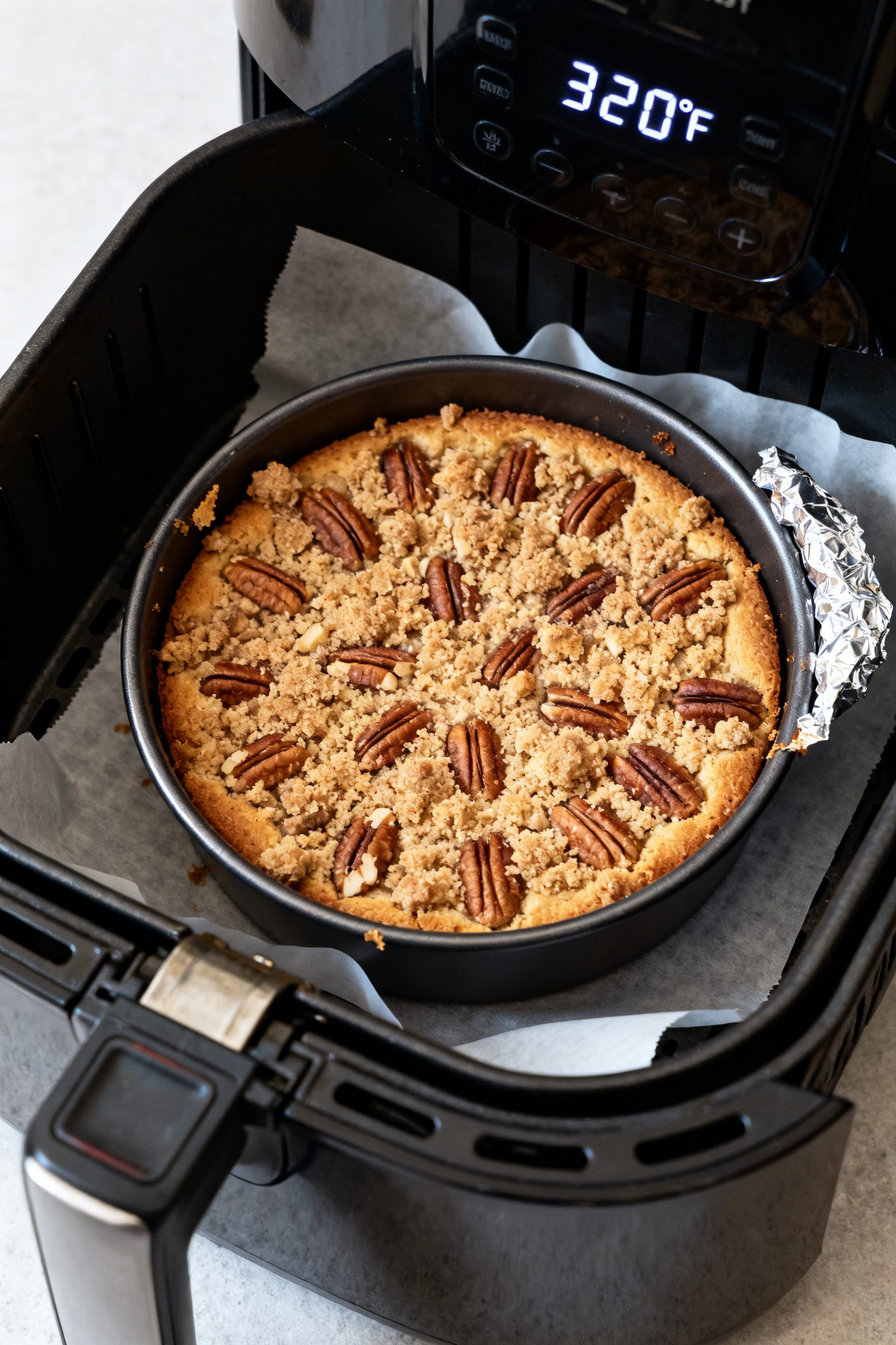 Cooking process: Overhead shot of the 6–7 inch round cake in its pan inside an air fryer basket mi