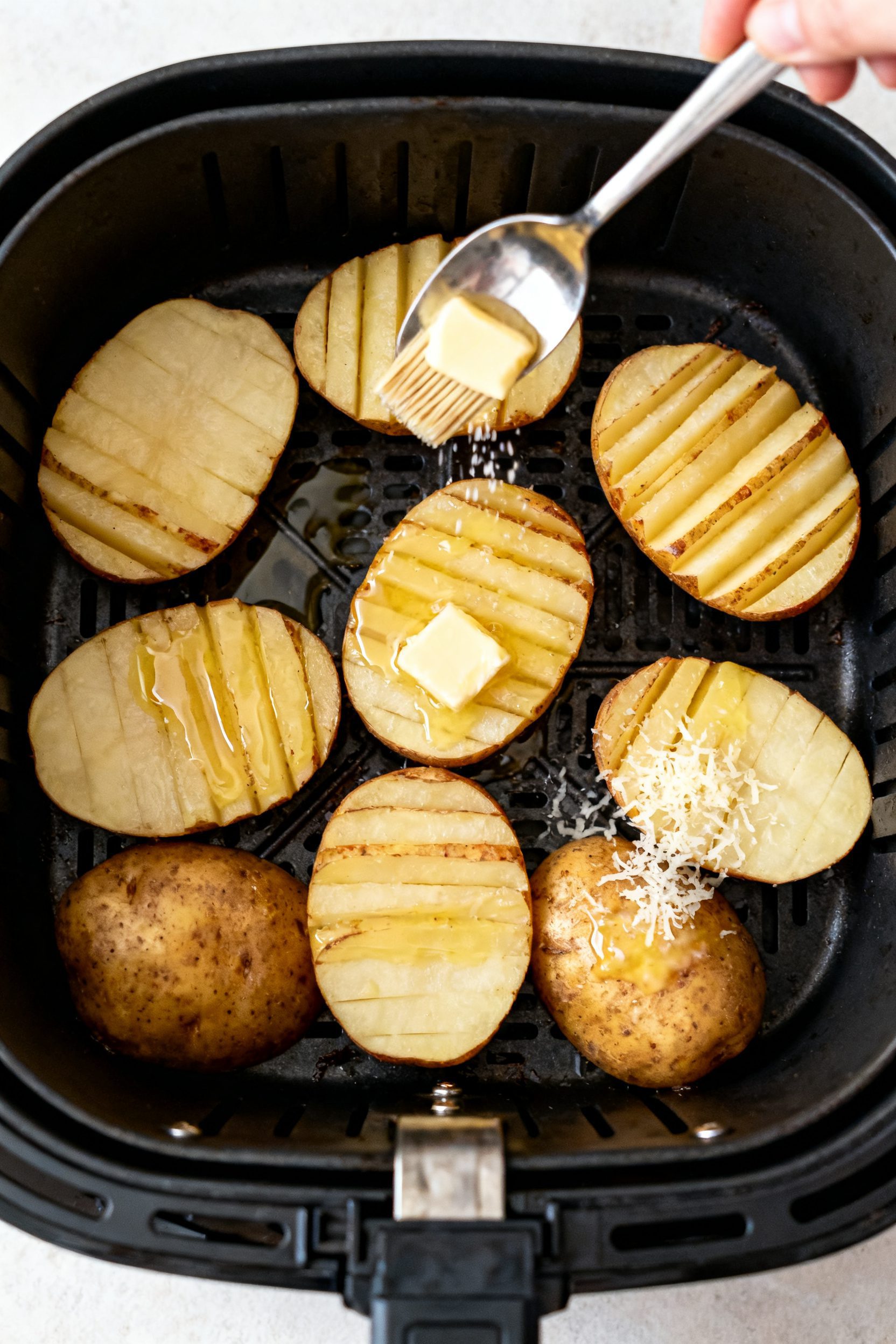 Cooking process: Overhead shot of the air fryer basket mid-cook, potatoes arranged cut-side up in a 