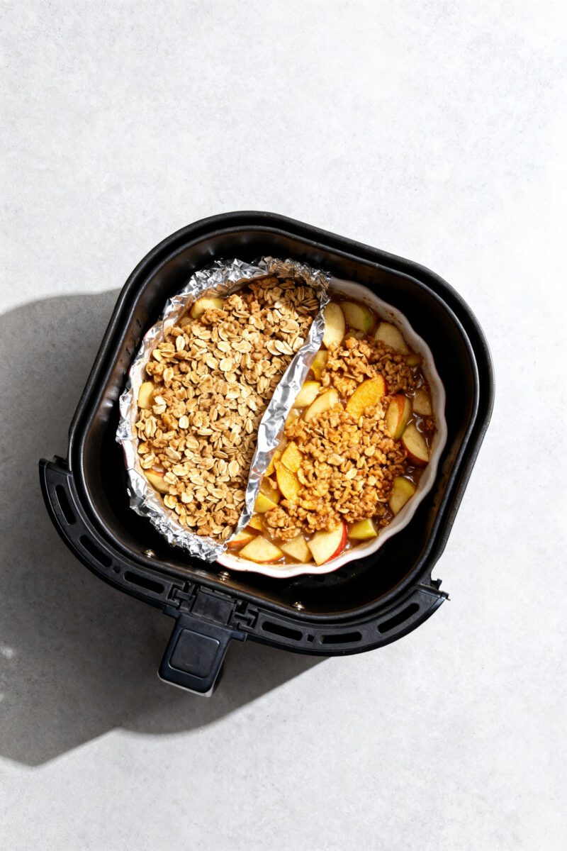 Cooking process: Overhead shot of the assembled apple crisp mid-cook in an air fryer at 350°F—top