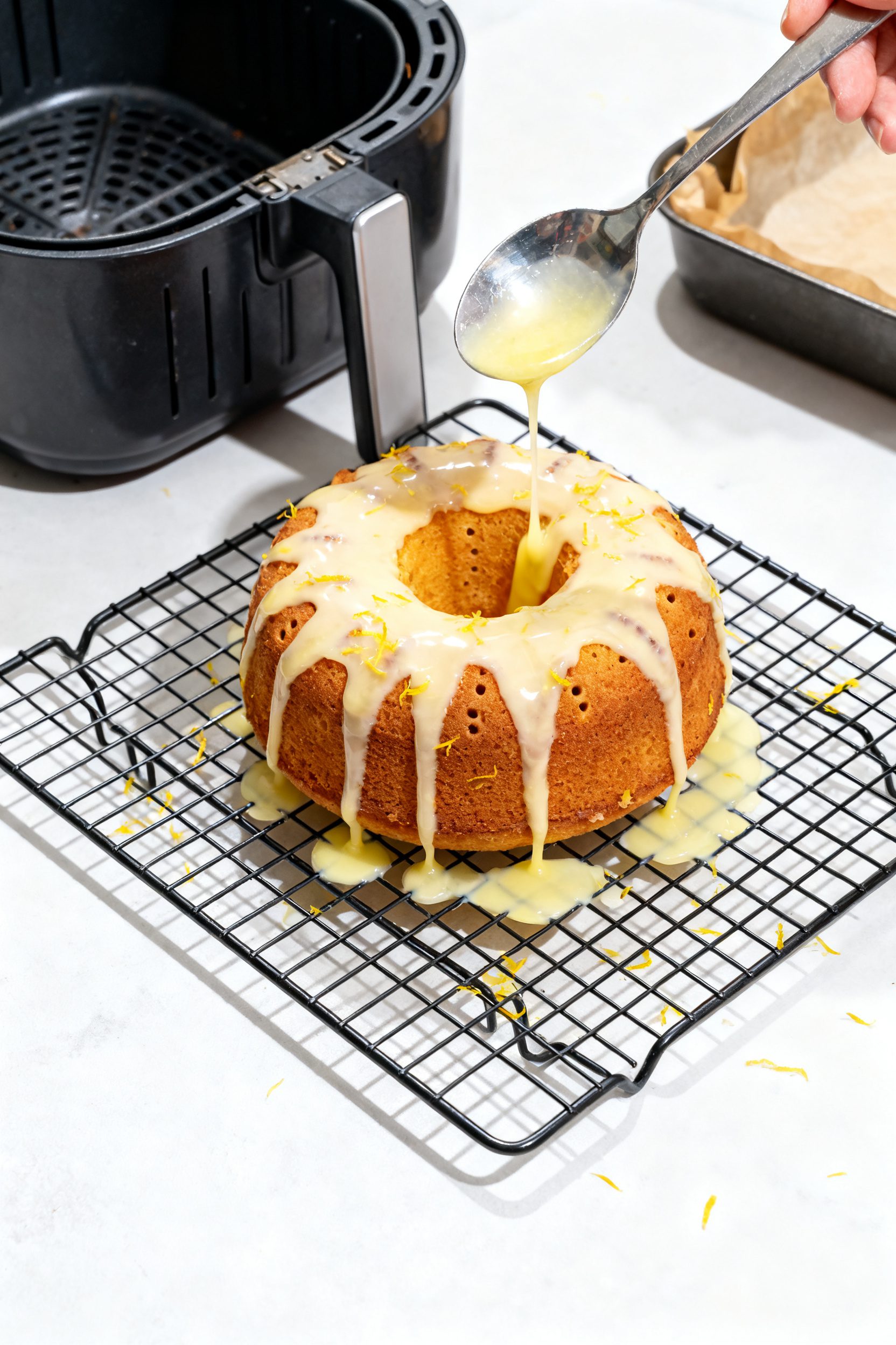 Cooking process: Overhead shot of the small round cake set on a wire rack while the opaque lemon dri
