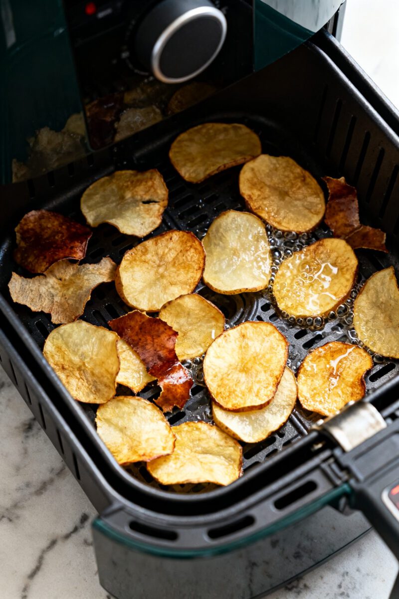 Cooking process: Potato peel chips mid-cook in an air fryer at 375°F, arranged in a loose, even lay