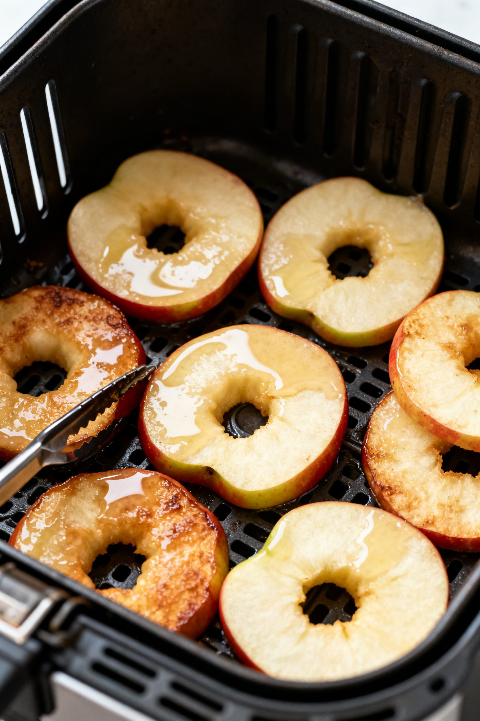 Cooking process shot: Batter-dipped apple rings arranged in a single, spaced layer in an air fryer b