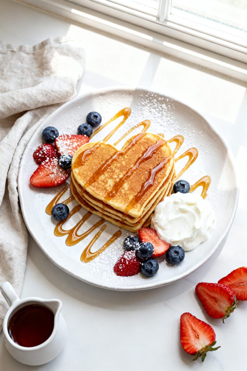 Final dish presentation: Restaurant-quality plated stack of heart-shaped pancake bites on a white ce