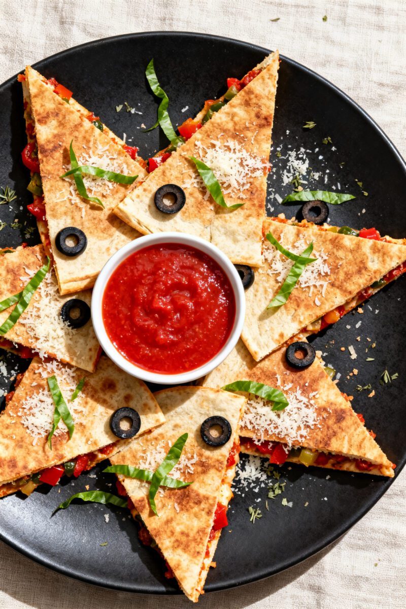 Overhead tasty top view: Sliced air fryer pizza quesadilla arranged in a star pattern on a matte bla