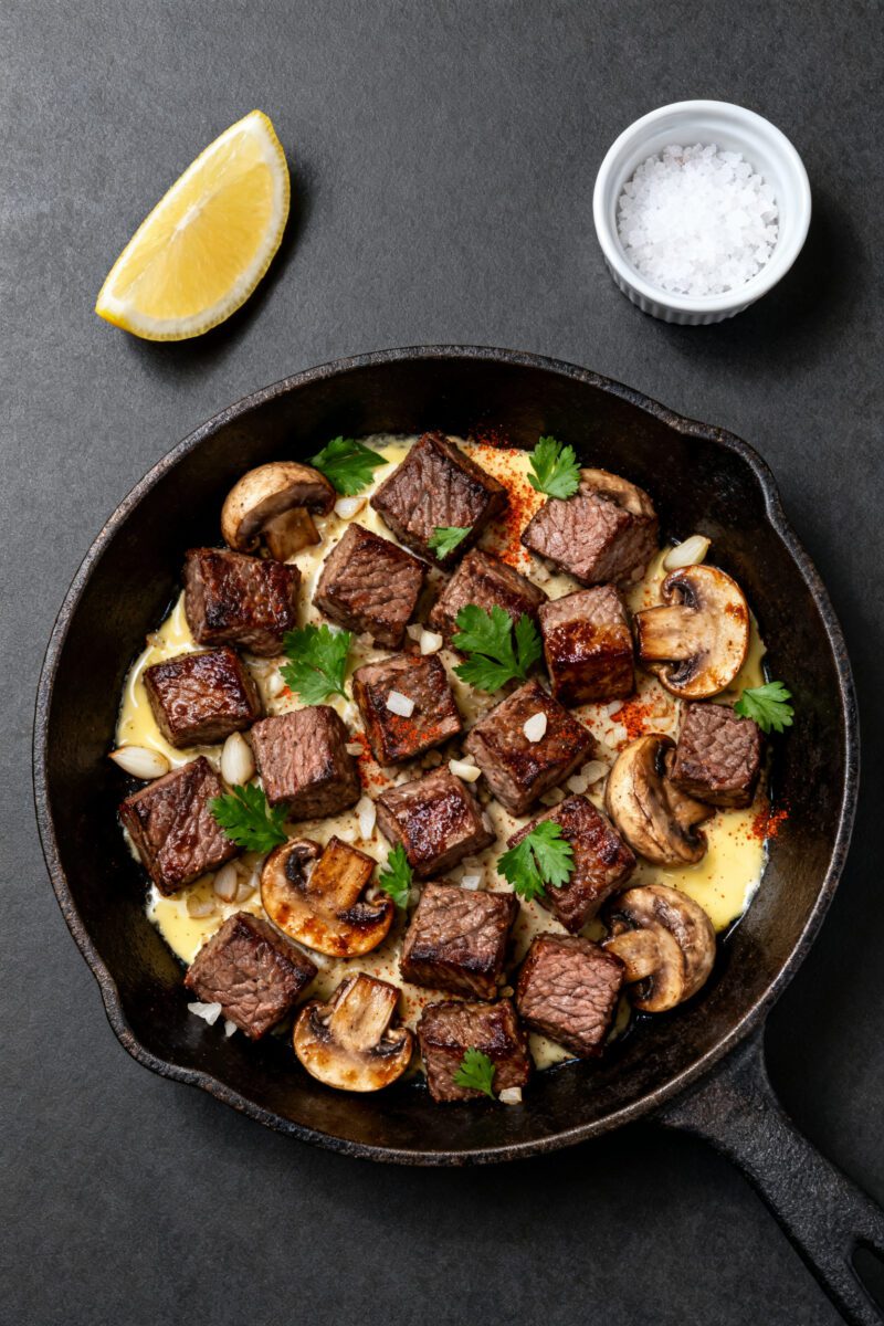 Overhead “tasty top view”: Top-down shot of the completed steak bites and mushrooms served famil