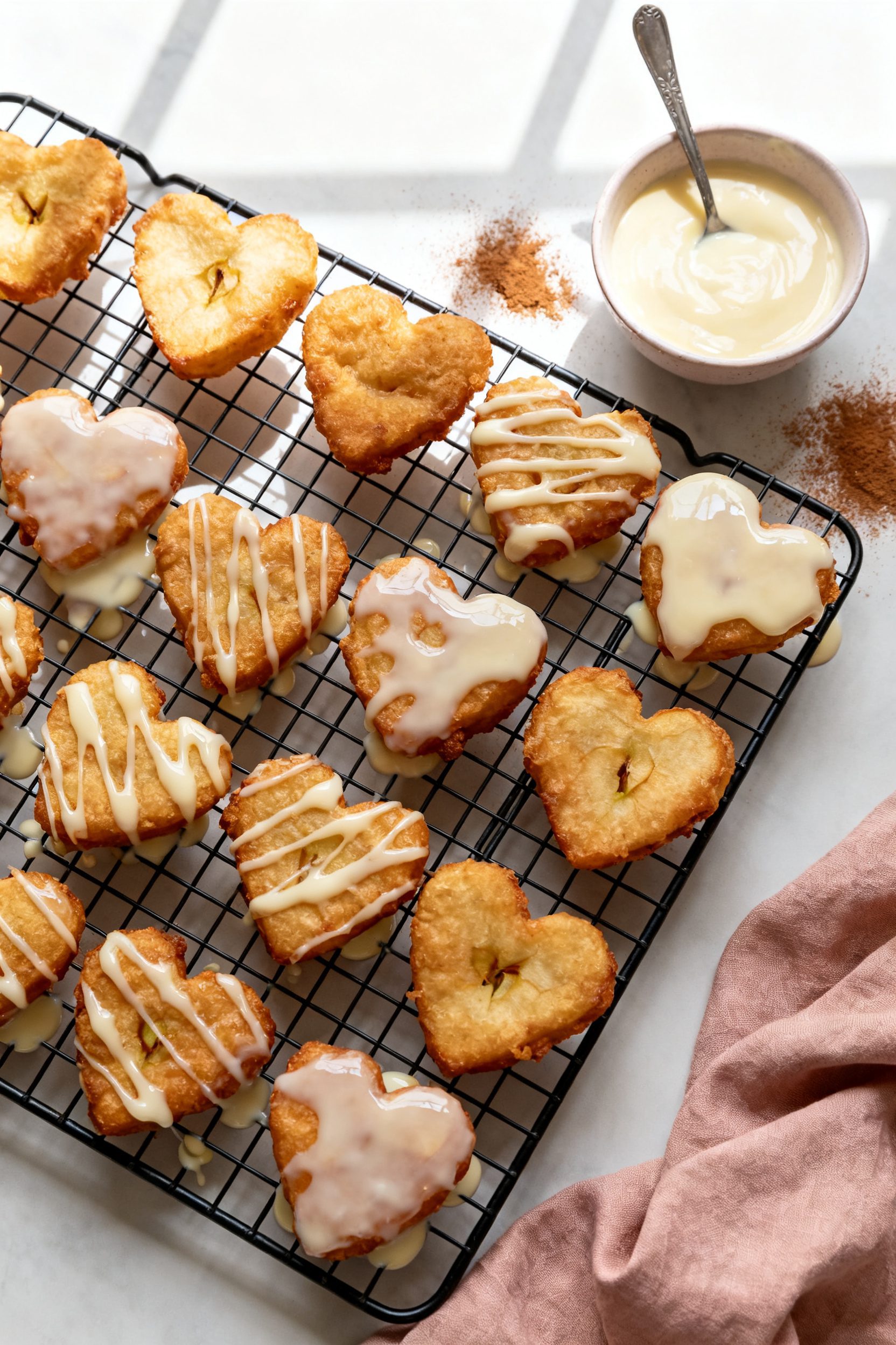 Tasty top view (overhead): A cooling rack filled with uniformly shaped heart apple fritters being dr