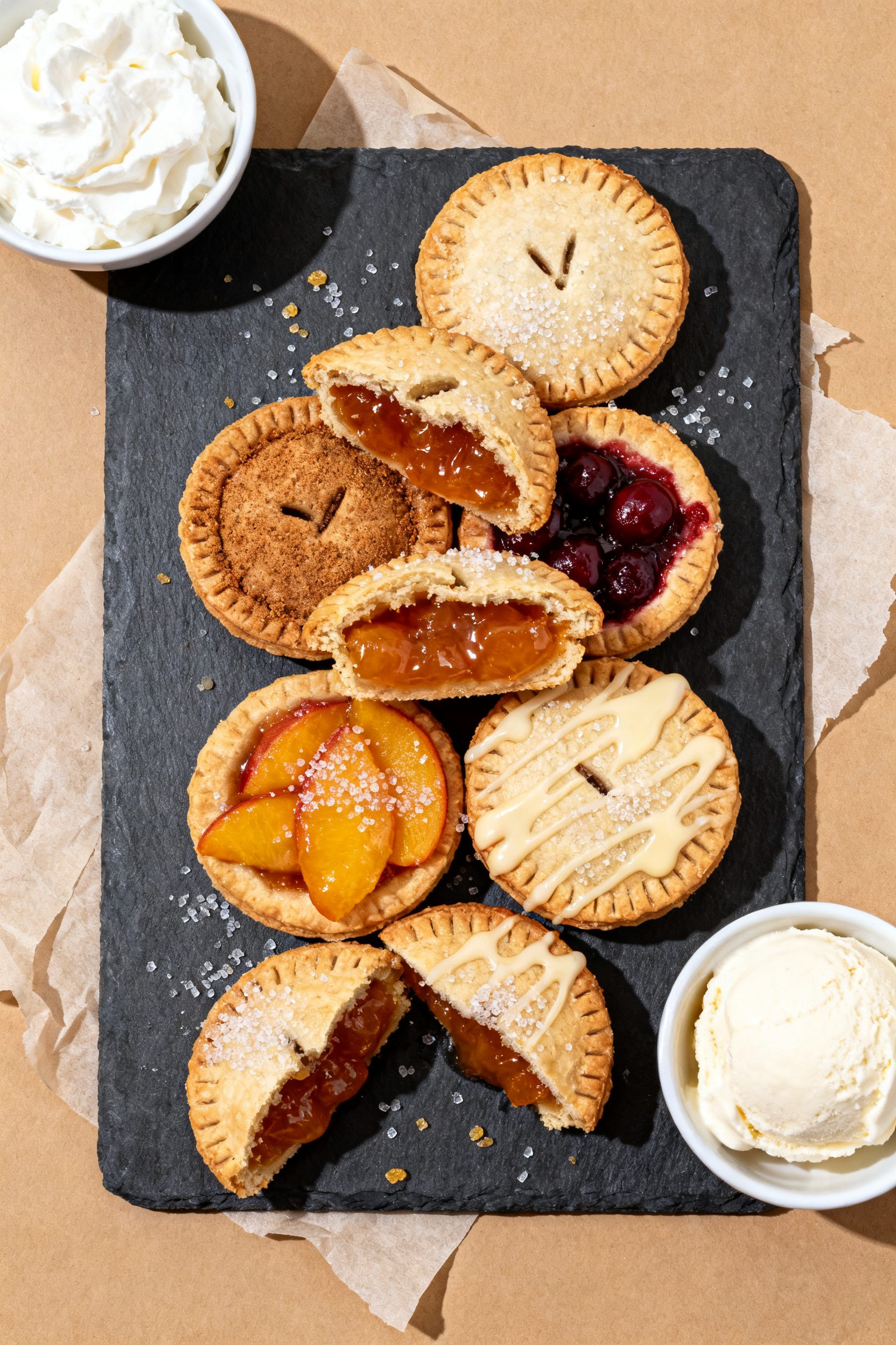 Tasty top view: Overhead shot of assorted mini hand pies on a matte slate serving board—apple-cinn