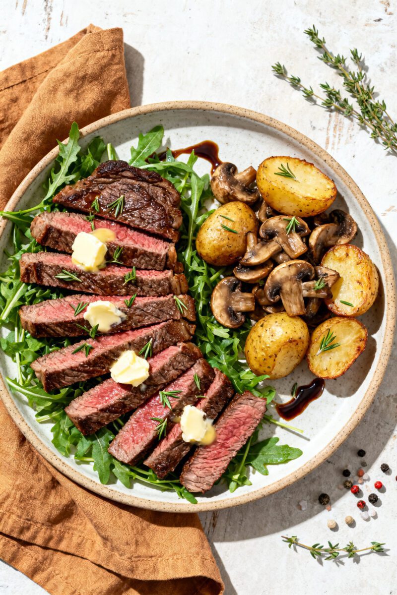 Tasty top view: Overhead shot of finished venison steak plated and sliced against the grain, fanned