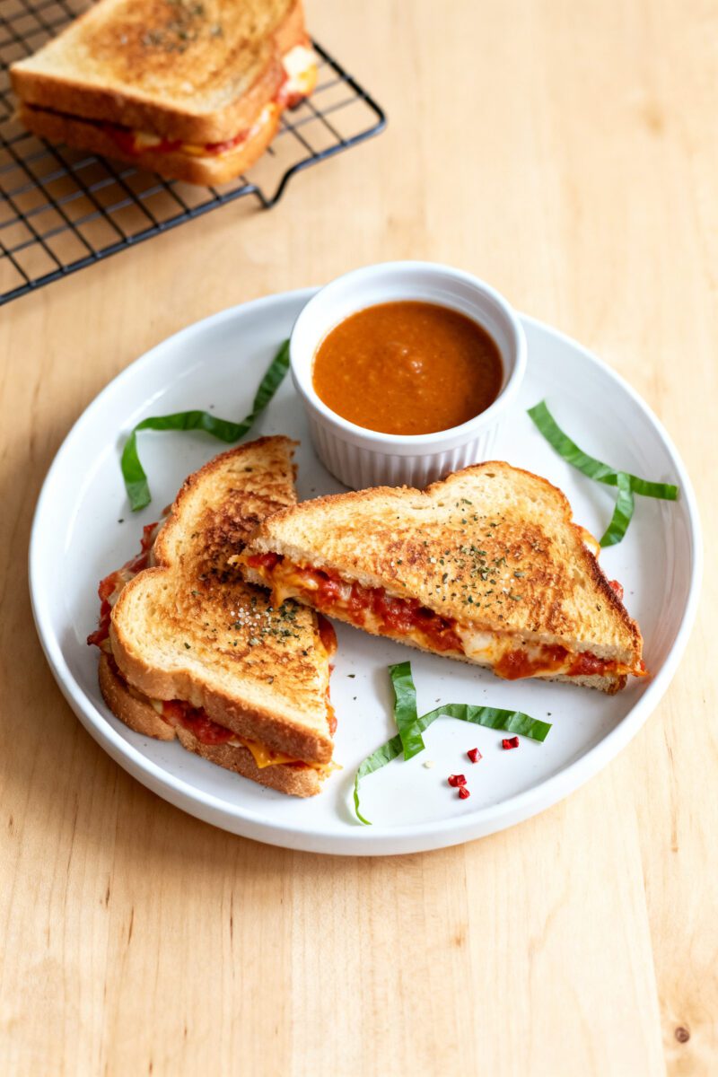 Air fryer garlic toast pizza sandwiches with crispy golden garlic bread, melted mozzarella cheese, rich pizza sauce, and Italian seasoning, served with marinara dipping sauce for a quick comfort food meal.