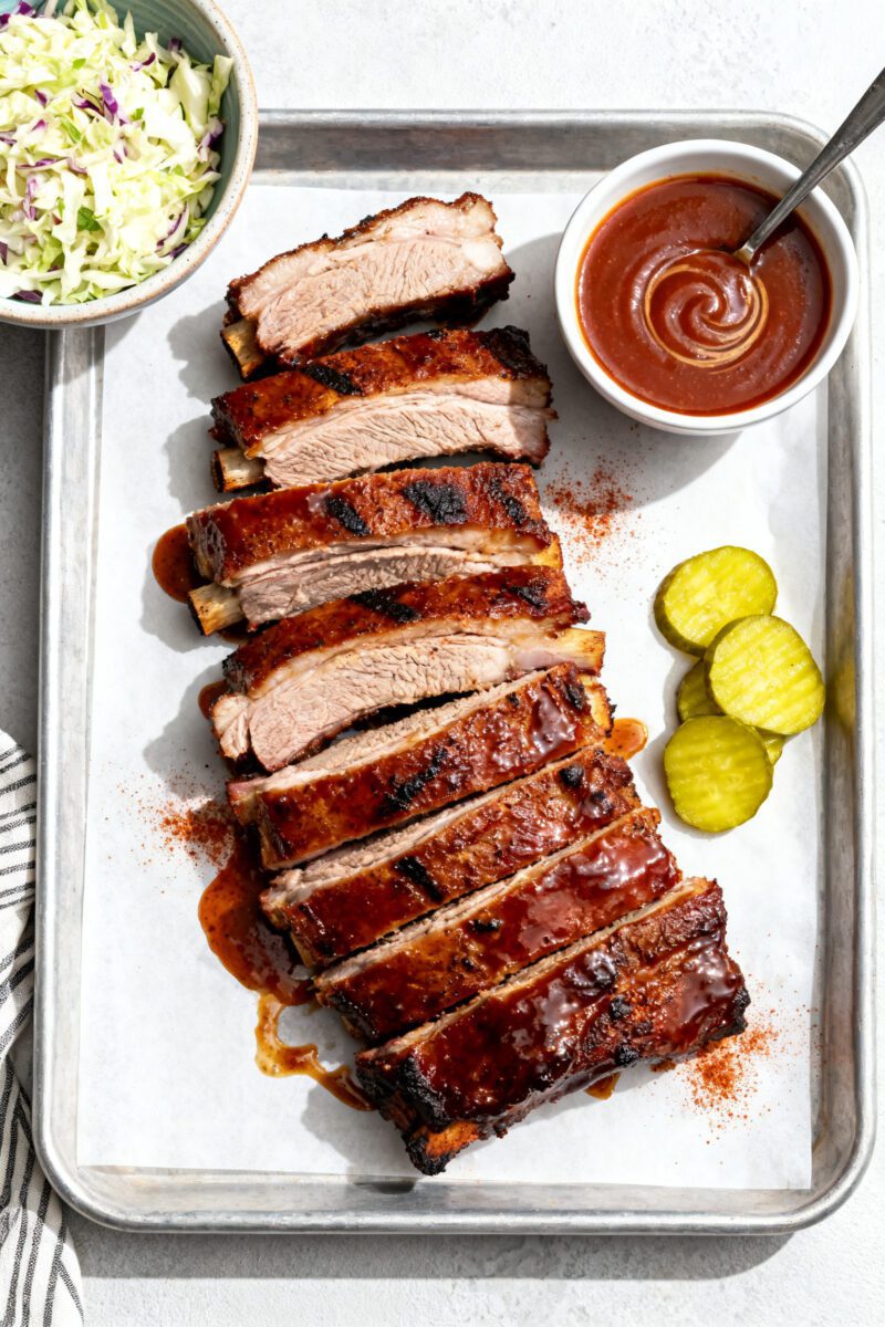 Air fryer barbecue pork ribs glazed with smoky sauce and served with pickles, coleslaw, and extra barbecue sauce
