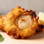 Air fryer onion bhaji with crispy golden onion fritters, tender onion layers, lightly spiced batter, fresh cilantro, and a lemon wedge, served as a flavorful Indian inspired appetizer.