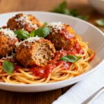 Air fryer spaghetti and meatballs with tender spaghetti, juicy browned meatballs, rich marinara sauce, grated parmesan cheese, and fresh basil, served as a comforting Italian inspired dinner.