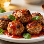 Air fryer Italian sausage meatballs with crispy browned exteriors, juicy sausage centers, rich marinara sauce, and fresh basil leaves, served as a flavorful Italian inspired appetizer or dinner.