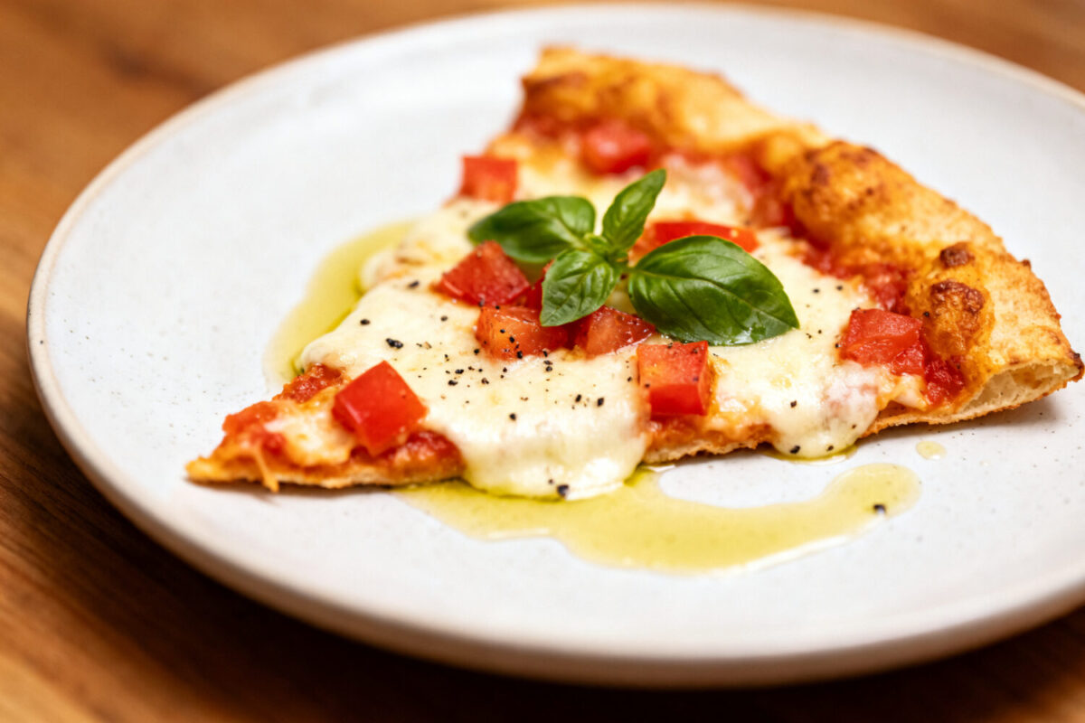 Air fryer low carb tortilla pizza with a crispy thin tortilla crust, melted mozzarella cheese, diced tomatoes, fresh basil, and olive oil, served as a quick keto friendly meal.