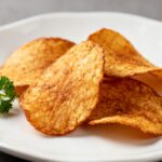 Air fryer low carb chips with crispy golden seasoned chips, lightly browned edges, and fresh parsley garnish, served as a crunchy keto friendly snack.