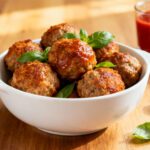 Air fryer homemade meatballs with juicy browned meatballs, rich tomato sauce, fresh basil leaves, and a bowl of marinara, served as a family friendly appetizer or dinner.