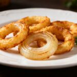 Air fryer low carb onion rings with a crispy golden coating, tender sweet onion centers, and fresh parsley garnish, served as a crunchy keto friendly appetizer or side dish.