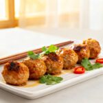 Air fryer Asian meatballs with juicy browned meatballs, a glossy savory glaze, fresh cilantro, sliced red chili peppers, and chopsticks, served as a flavorful appetizer or weeknight dinner.