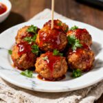 Air fryer BBQ meatballs with juicy browned meatballs coated in a rich barbecue sauce, fresh parsley garnish, and extra sauce drizzled on top, served as an easy appetizer or weeknight dinner.