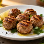 Air fryer keto meatballs with juicy browned meatballs, fresh parsley, cracked black pepper, olive oil, and a lemon wedge, served as a high protein low carb dinner.