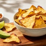Air fryer low carb tortilla chips with crispy golden tortilla triangles, lime wedges, and fresh salsa, served as a crunchy keto friendly snack or appetizer.