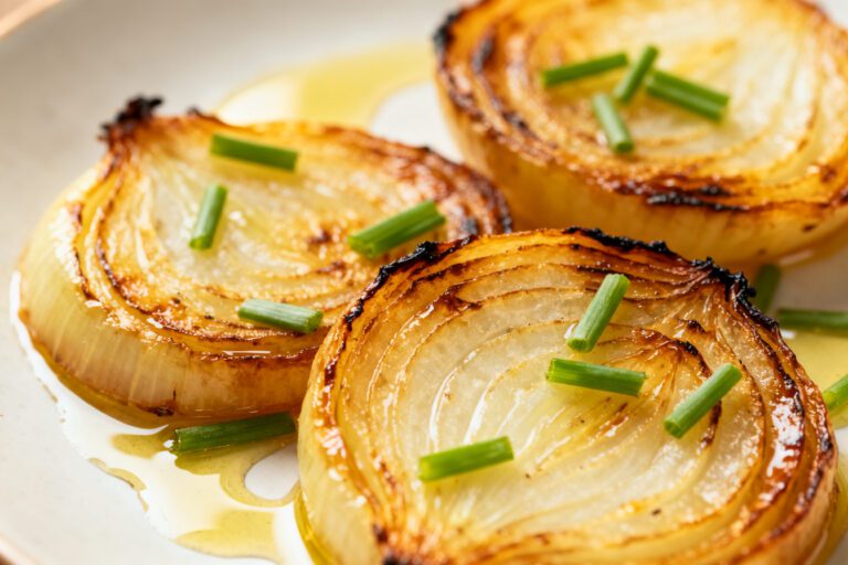 Air fryer grilled onions with sweet caramelized onion halves, lightly charred edges, fresh chives, and a drizzle of olive oil, served as an easy and flavorful vegetable side dish.