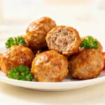 Air fryer pork meatballs with juicy browned pork meatballs, tender interior, fresh parsley garnish, and cherry tomatoes, served as an easy family friendly appetizer or weeknight dinner.
