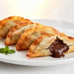 Air fryer Nutella wontons with crispy golden wonton wrappers, warm gooey chocolate hazelnut filling, fresh mint garnish, and light steam, served as an easy dessert.