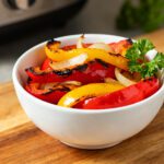 Air fryer bell peppers and onions with tender roasted red, yellow, and orange bell peppers, sweet caramelized onions, and fresh parsley, served as a quick and flavorful vegetable side dish.