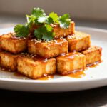 Air fryer bang bang tofu with crispy golden tofu cubes, creamy sweet and spicy bang bang sauce, sesame seeds, and fresh cilantro, served as an easy high protein vegetarian dinner.