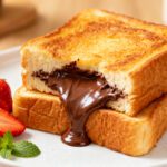 Air fryer Nutella bread with golden toasted bread, warm gooey chocolate hazelnut filling, and fresh strawberries, served as an easy sweet breakfast or dessert.