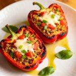 Air fryer vegetarian stuffed peppers with roasted red bell peppers filled with quinoa, tomatoes, melted cheese, fresh green onions, and basil, served as a healthy meatless dinner.