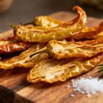 Air fryer dehydrated peppers with dried sweet pepper halves, wrinkled tender texture, fresh rosemary, and coarse salt, served as a homemade pantry staple for cooking and seasoning.