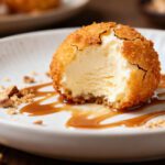 Air fryer deep fried ice cream with a crispy golden coating, creamy vanilla ice cream center, caramel drizzle, and chopped nuts, served as a restaurant style homemade dessert.