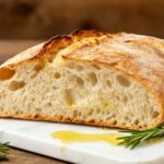 Air fryer ciabatta bread with a crispy golden crust, chewy airy crumb, rosemary sprigs, and olive oil, served as a rustic homemade Italian bread.