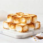 Air fryer dehydrated marshmallows with toasted golden marshmallows featuring a light crunchy texture, stacked on a marble board and served as a sweet homemade snack.