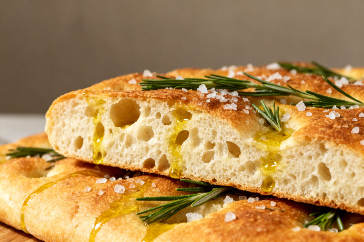 Air fryer focaccia bread with a crispy golden crust, chewy airy crumb, rosemary sprigs, flaky sea salt, and olive oil, served as a rustic homemade Italian bread.