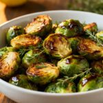 Air fryer balsamic Brussels sprouts with crispy caramelized Brussels sprouts, glossy balsamic glaze, fresh rosemary, and lemon wedges, served as a flavorful vegetable side dish.
