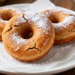 Air fryer gluten free donuts with a light fluffy texture, golden baked exterior, and a dusting of powdered sugar, served as an easy homemade gluten free dessert.