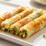 Air fryer rice paper rolls with crispy golden wrappers, fresh vegetables, herbs, and a light dipping sauce, served as a crunchy appetizer or light vegetarian meal.